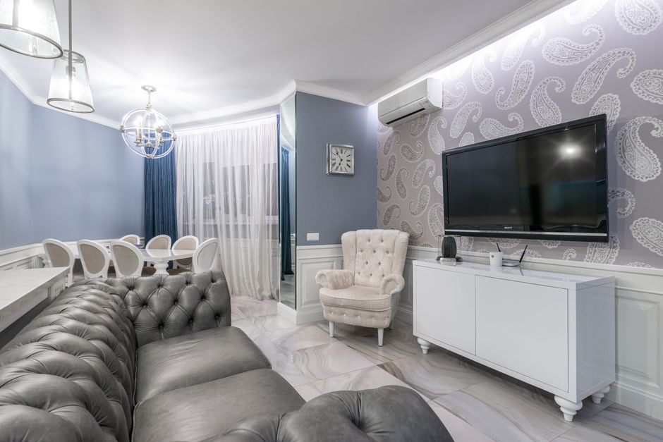 Comfortable gray leather sofa placed in front of TV with black screen in spacious living room in luxury flat